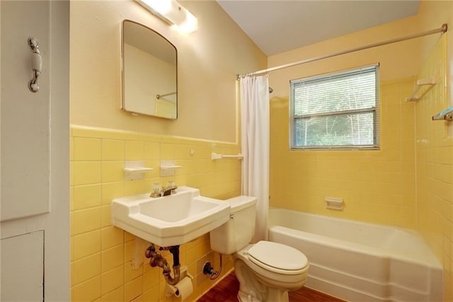 bathroom with tile walls, shower / tub combo with curtain, and toilet