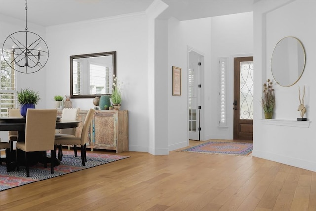 entryway featuring ornamental molding, a wealth of natural light, an inviting chandelier, and light hardwood / wood-style flooring