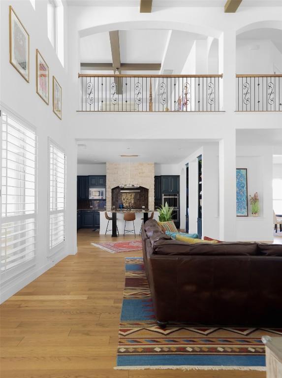 2520 Ionian Cv, Austin, TX 78730 - living room featuring a high ceiling, plenty of natural light, light wood-style floors, a stone fireplace, and beam ceiling