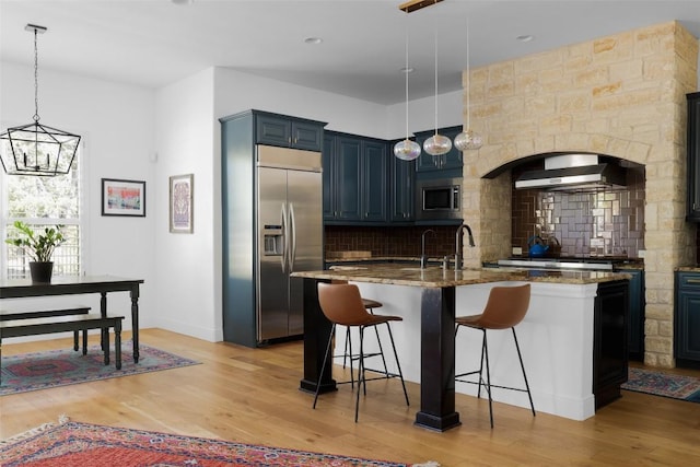 2520 Ionian Cv, Austin, TX 78730 - kitchen with built in appliances, decorative backsplash, dark stone counters, a kitchen bar, and light wood finished floors