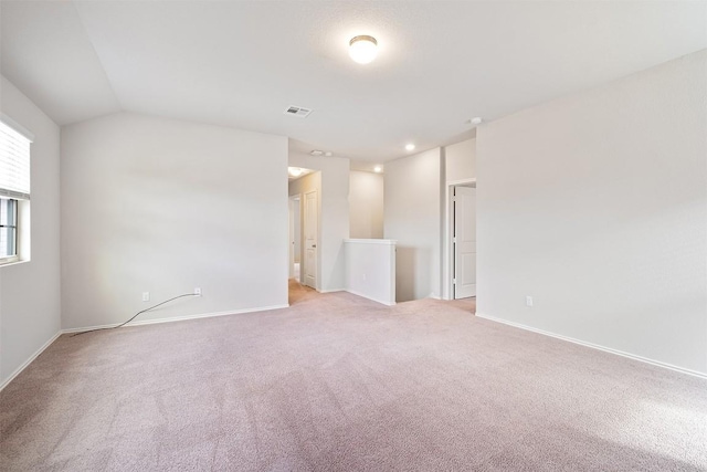 spare room featuring lofted ceiling and light carpet