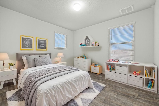 bedroom with multiple windows, a textured ceiling, and dark hardwood / wood-style flooring