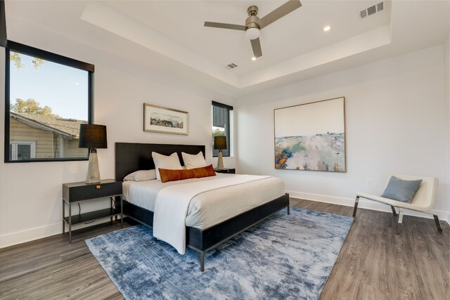 bedroom with hardwood / wood-style floors, a raised ceiling, and ceiling fan