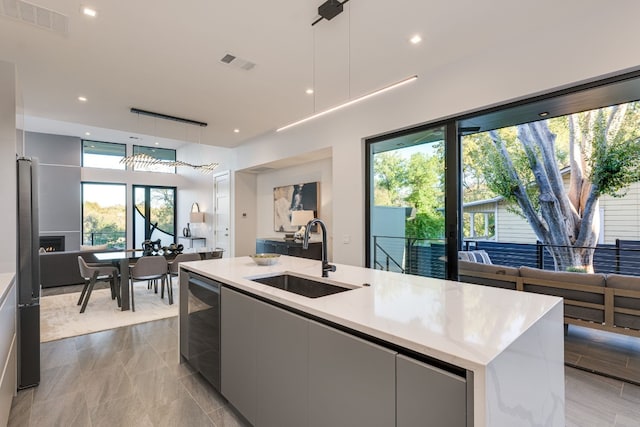 kitchen with pendant lighting, an island with sink, sink, and white cabinets