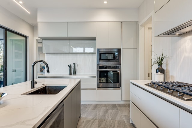 kitchen featuring sink, appliances with stainless steel finishes, light stone counters, tasteful backsplash, and white cabinets