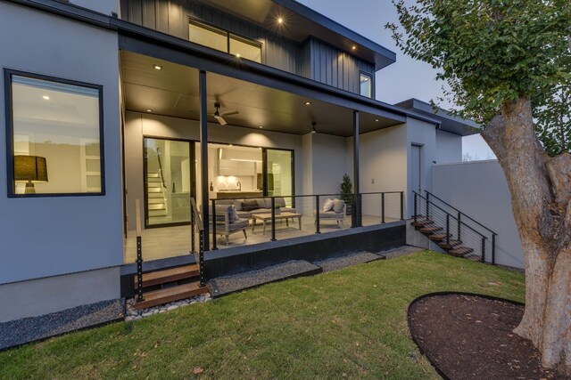 rear view of property featuring ceiling fan and a lawn