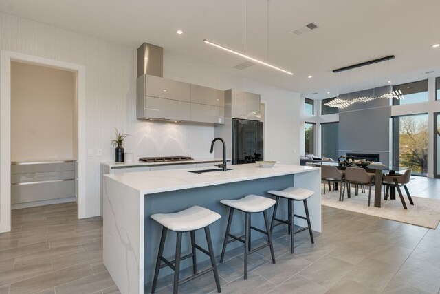 kitchen featuring gray cabinets, a kitchen bar, pendant lighting, and stainless steel gas stovetop