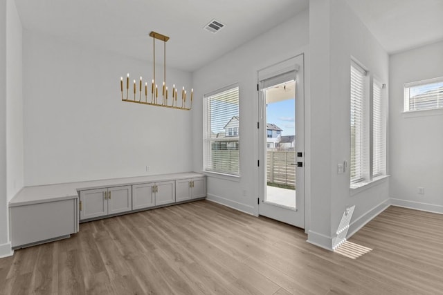 unfurnished dining area featuring a notable chandelier and light hardwood / wood-style floors