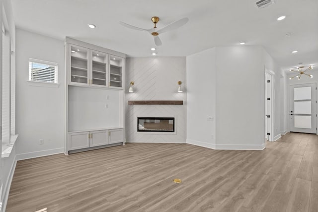 unfurnished living room featuring a fireplace, light hardwood / wood-style floors, and ceiling fan