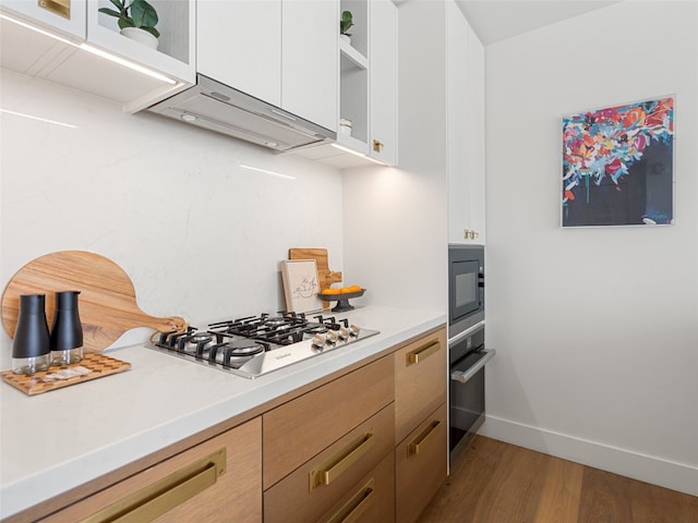 70 Rainey St Unit 1705, Austin, TX 78701 - kitchen with appliances with stainless steel finishes, wood finished floors, light countertops, and open shelves