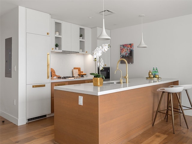 kitchen with white gas stovetop, white cabinetry, sink, electric panel, and light hardwood / wood-style floors