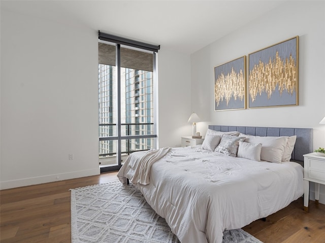 bedroom featuring expansive windows and hardwood / wood-style flooring