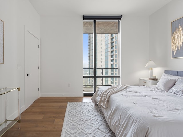 bedroom with dark hardwood / wood-style flooring and a wall of windows