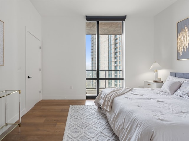 70 Rainey St Unit 1705, Austin, TX 78701 - bedroom featuring multiple windows, wood finished floors, expansive windows, and baseboards