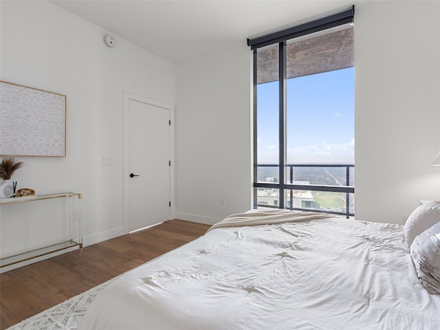 bedroom with dark wood-type flooring and expansive windows