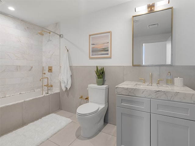 full bathroom with toilet, tiled shower / bath, tile walls, vanity, and tile patterned flooring