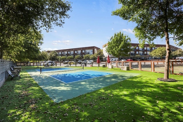 view of property's community with a tennis court, fence, and a lawn