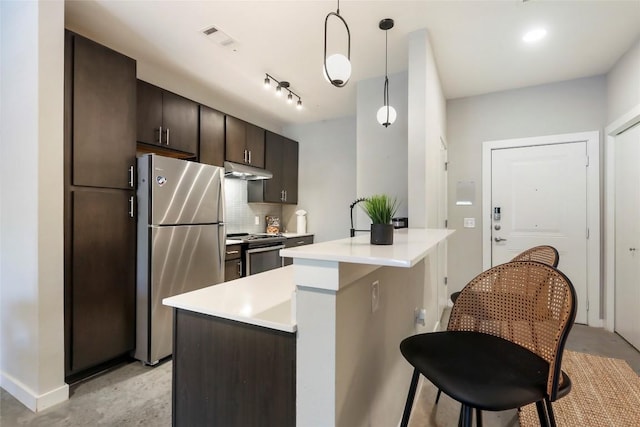 kitchen featuring appliances with stainless steel finishes, tasteful backsplash, hanging light fixtures, a center island, and dark brown cabinetry