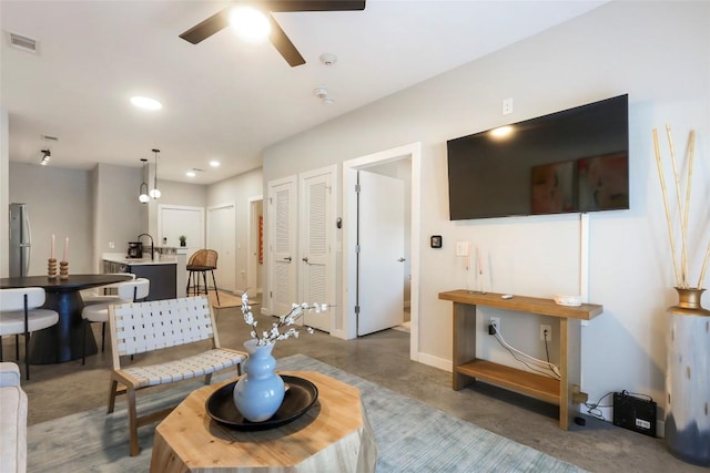 living room with ceiling fan, concrete flooring, and sink