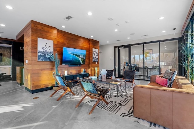 living area with concrete flooring, wooden walls, visible vents, and recessed lighting