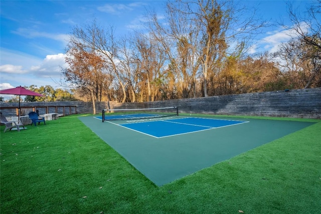 view of tennis court featuring fence and a lawn