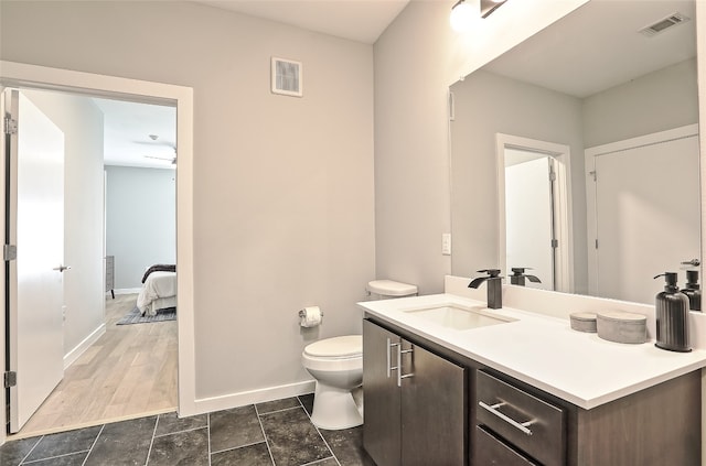 bathroom featuring baseboards, visible vents, vanity, and toilet