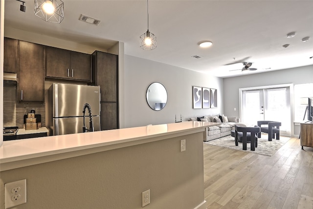 kitchen featuring light wood finished floors, light countertops, visible vents, freestanding refrigerator, and dark brown cabinetry