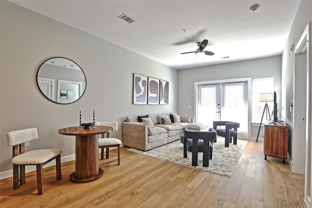 living room featuring light wood-style floors, visible vents, ceiling fan, and baseboards