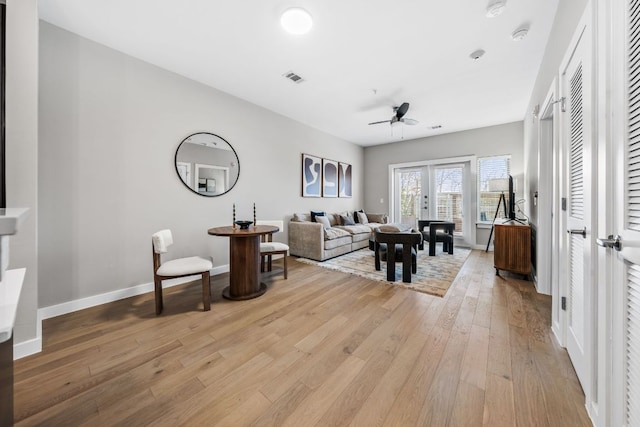 living room featuring visible vents, baseboards, light wood-style flooring, and a ceiling fan