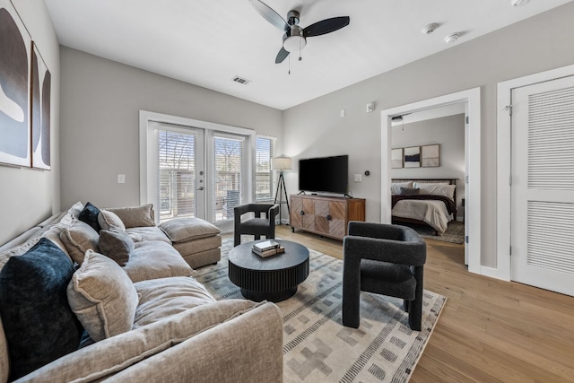 living area with french doors, baseboards, a ceiling fan, and light wood finished floors