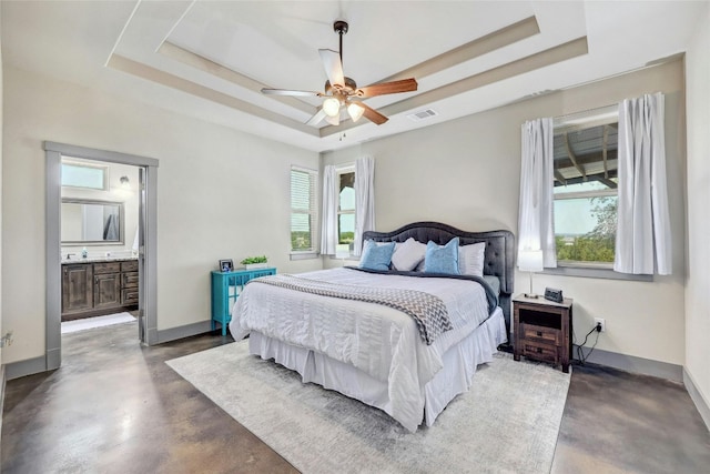 bedroom featuring multiple windows, connected bathroom, and a tray ceiling