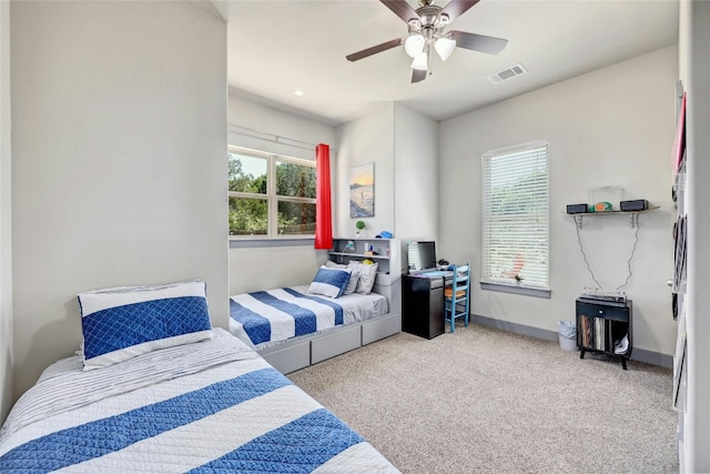 carpeted bedroom featuring multiple windows and ceiling fan