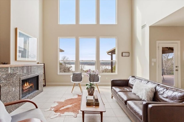 living room featuring a high ceiling, a tile fireplace, and light tile patterned flooring