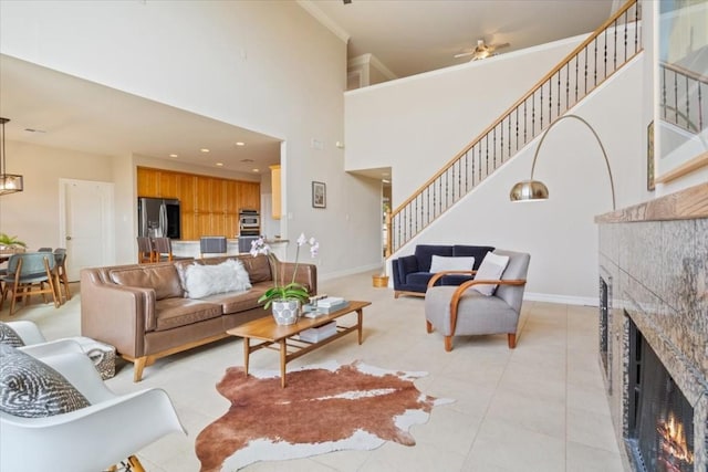 tiled living room with crown molding, ceiling fan, a tile fireplace, and a high ceiling