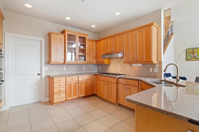 kitchen with stone countertops, stainless steel gas stovetop, sink, backsplash, and light tile patterned floors