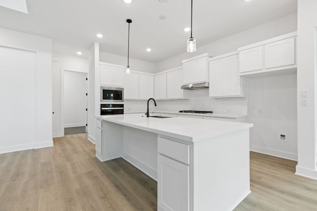 118 Bateleurfrey Cv, Cedar Creek, TX 78612 - kitchen featuring oven, stainless steel microwave, under cabinet range hood, light wood-style flooring, and white cabinetry