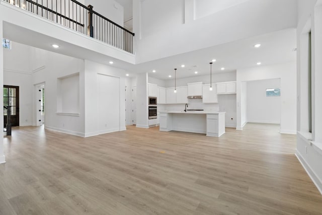 118 Bateleurfrey Cv, Cedar Creek, TX 78612 - unfurnished living room featuring a towering ceiling, light wood finished floors, and recessed lighting