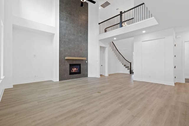 118 Bateleurfrey Cv, Cedar Creek, TX 78612 - unfurnished living room featuring a high ceiling, stairway, ceiling fan, wood finished floors, and a tile fireplace