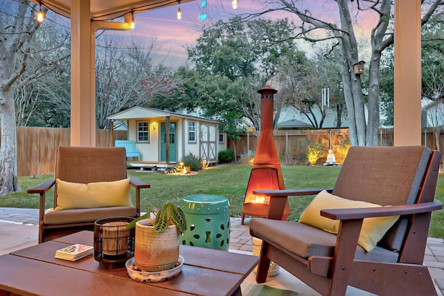 patio terrace at dusk featuring an outdoor structure and a lawn