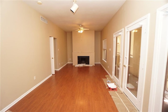 unfurnished living room featuring ceiling fan, a large fireplace, and hardwood / wood-style floors