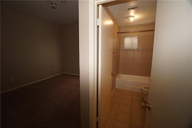 bathroom with tiled shower / bath, toilet, and tile patterned flooring