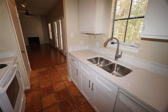 kitchen with sink, dishwasher, white cabinetry, range with electric cooktop, and a fireplace