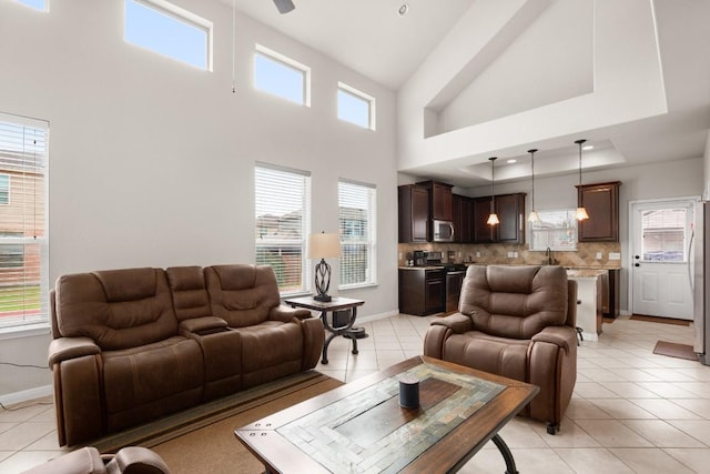 living room featuring light tile patterned flooring, plenty of natural light, sink, and a tray ceiling