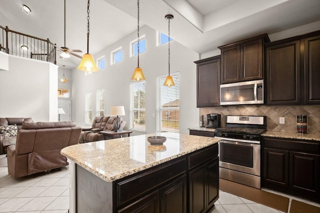 kitchen with dark brown cabinetry, a center island, appliances with stainless steel finishes, pendant lighting, and decorative backsplash