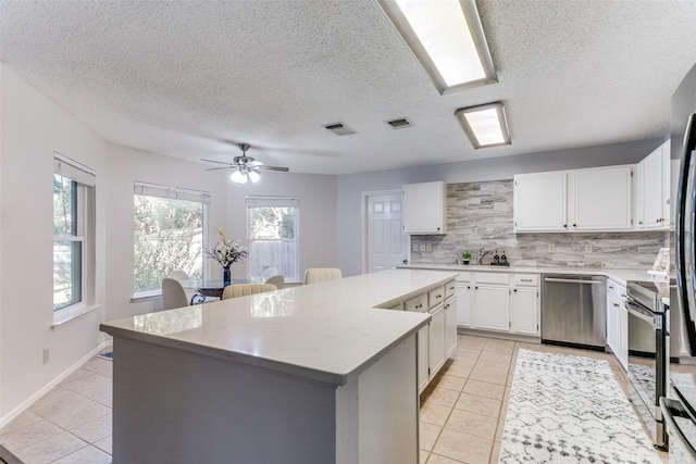 kitchen with light tile patterned flooring, appliances with stainless steel finishes, a center island, and white cabinets