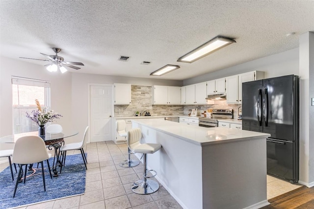 kitchen featuring black refrigerator, white cabinetry, backsplash, a center island, and electric stove