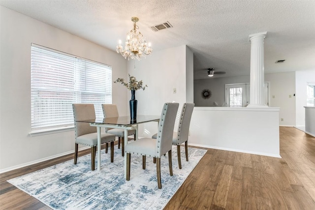 dining area featuring an inviting chandelier, decorative columns, hardwood / wood-style floors, and a textured ceiling