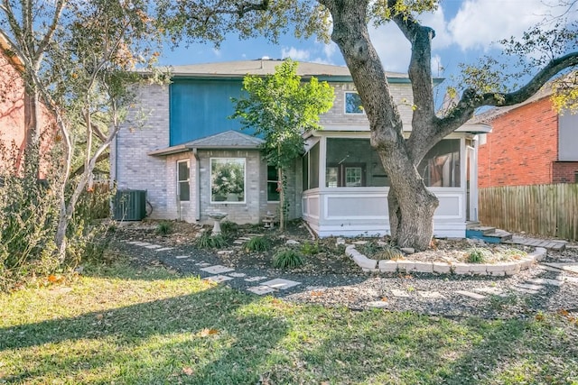 view of front of house featuring central AC unit, a sunroom, and a front yard