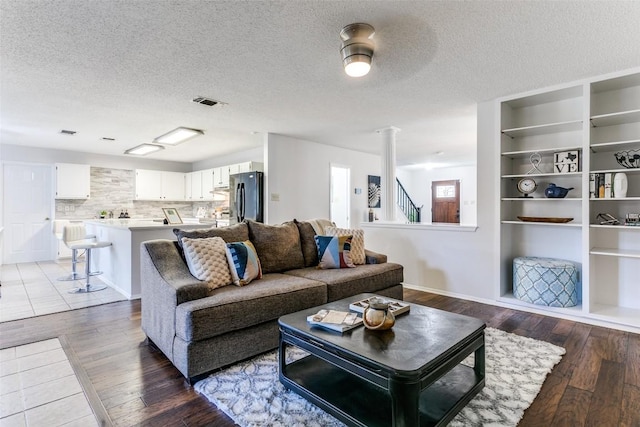 living room with decorative columns, hardwood / wood-style floors, and a textured ceiling