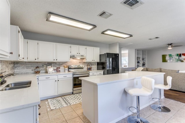 kitchen with sink, black refrigerator, white cabinetry, backsplash, and stainless steel electric stove